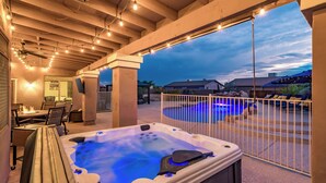 Ett bubbelbad med utsikt över en swimmingpool och hus i bakgrunden.