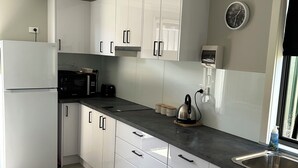 A modern kitchen with white cabinets, a black countertop, and a stainless steel sink. - A Little Southern Comfort - granny flat in Sanctuary Point  (Sanctuary Point)