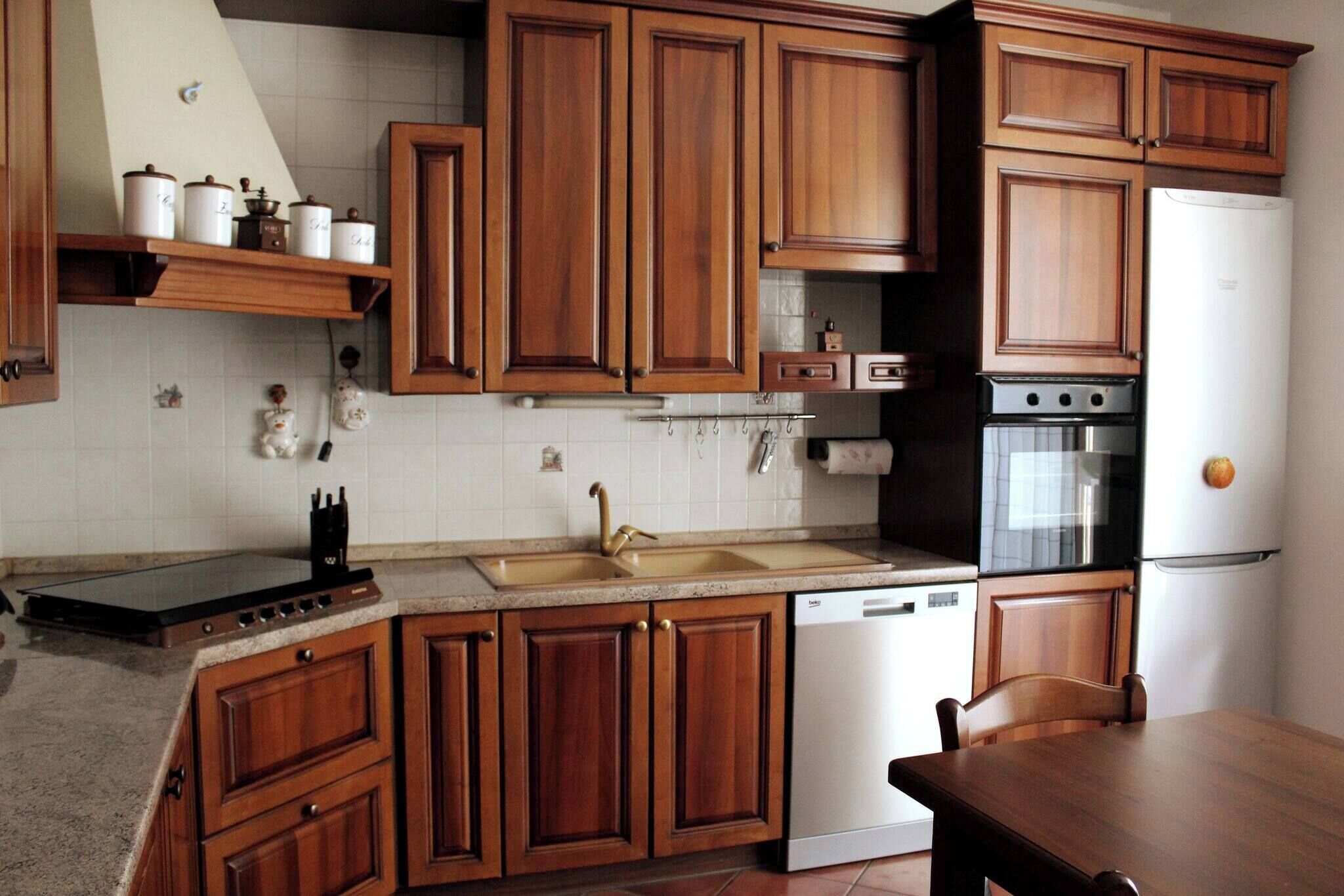 Una cocina con armarios de madera, un fregadero, un lavavajillas y una estufa.