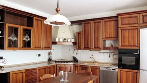 A kitchen with wooden cabinets, a stainless steel dishwasher, and a wooden dining table. - La Culla Tra I Vigneti - Stanza (Grazzano Badoglio)