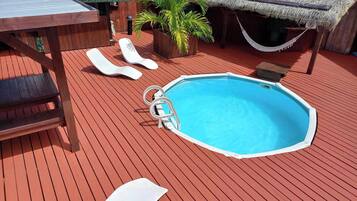 Une piscine avec des chaises longues et une terrasse en bois.