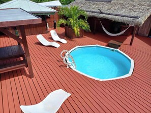 A swimming pool with lounge chairs and a wooden deck. - Bungalow Cosy, Calme et Reposant (Tahaa)