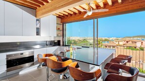 A modern kitchen with a large island, bar stools, and a view of the sea. - Villa Mirtillo with sea view and pool 400 mt from Golfo Aranci beach (Golfo Aranci)