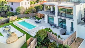 Una propiedad residencial moderna con piscina, mobiliario exterior y vista al mar.