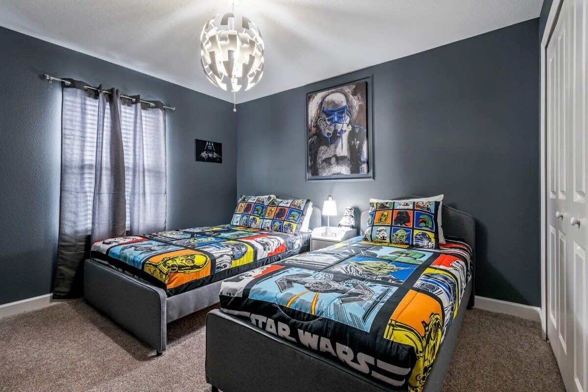 Een slaapkamer met twee bedden, een Star Wars bedovertrek, een globe lamp en een lijst met kunst aan de muur.