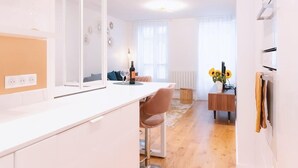 Eine moderne Küche mit weißer Arbeitsplatte, einer Glaseinfriedung und einem Essbereich aus Holz mit einer Vase voller Sonnenblumen.