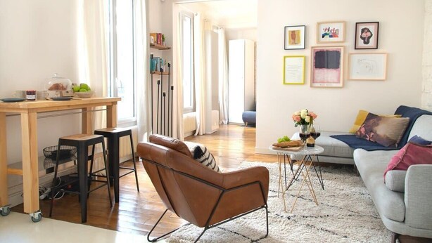 A modern living room with a sofa, a coffee table, and a dining area with a table and chairs. - Le Plaisir du Pantheon + Seine Cruise (Aug only!) (Paris)
