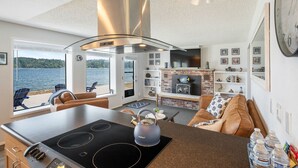 Een moderne keuken met een groot eiland, een roestvrijstalen afzuigkap en uitzicht op het meer.