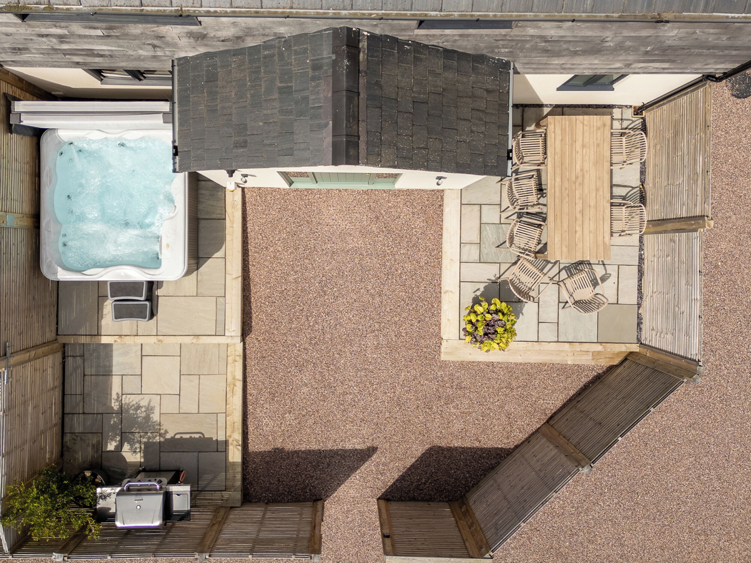 An aerial view of a backyard with a hot tub, outdoor seating area, and a small patio.