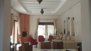 A living room with a sofa, armchairs, a dining table, and a TV. - Villa de Charme , Piscine Privée, Calme (Oulad hassoune - Marrakech)
