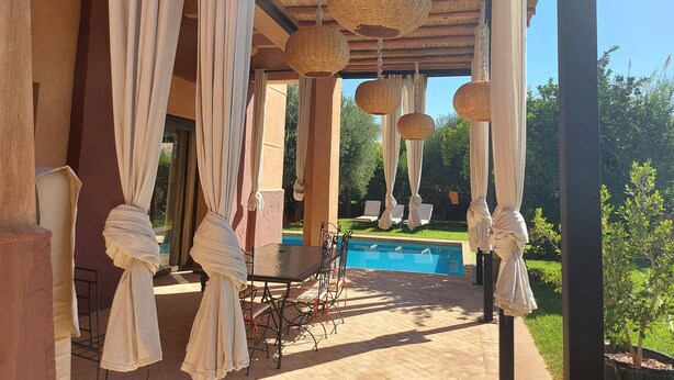 A covered outdoor seating area with a pool, featuring hanging wicker lamps and draped white curtains. - Villa de Charme , Piscine Privée, Calme (Oulad hassoune - Marrakech)