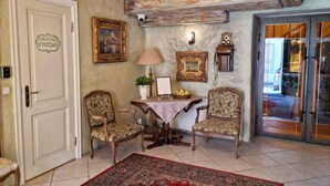 Ein Zimmer mit zwei Stühlen, einem Tisch mit einer Lampe, einem roten Teppich und einer Tür mit dem Schriftzug "LUCACE STORACE".
