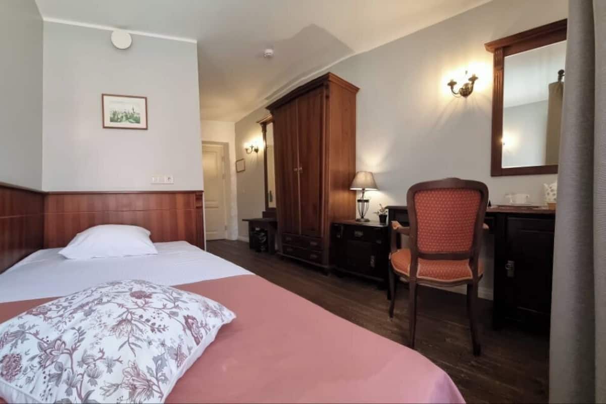 Une chambre d’hôtel comprenant un lit, un bureau, une chaise, une armoire et un miroir.