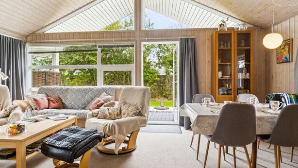 Een gezellige woonkamer met een bank, stoelen, een tafel en een boekenkast.