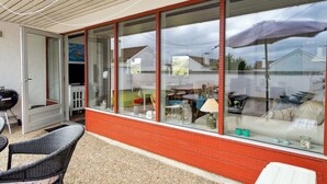 A covered patio area with a grill, wicker furniture, and a glass enclosure with a view of a backyard. - "Werna" - 900m from the sea by Interhome (Pandrup)