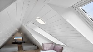 A sloped ceiling room with a television, a sofa, and a small table. - "Werna" - 900m from the sea by Interhome (Pandrup)
