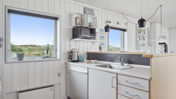 A modern kitchen with white cabinetry, a large window, and a view of the outdoors. - "Werna" - 900m from the sea by Interhome (Pandrup)