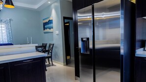 Una cocina moderna con un refrigerador de acero inoxidable, un comedor con mesa y sillas, y un cuadro en la pared.