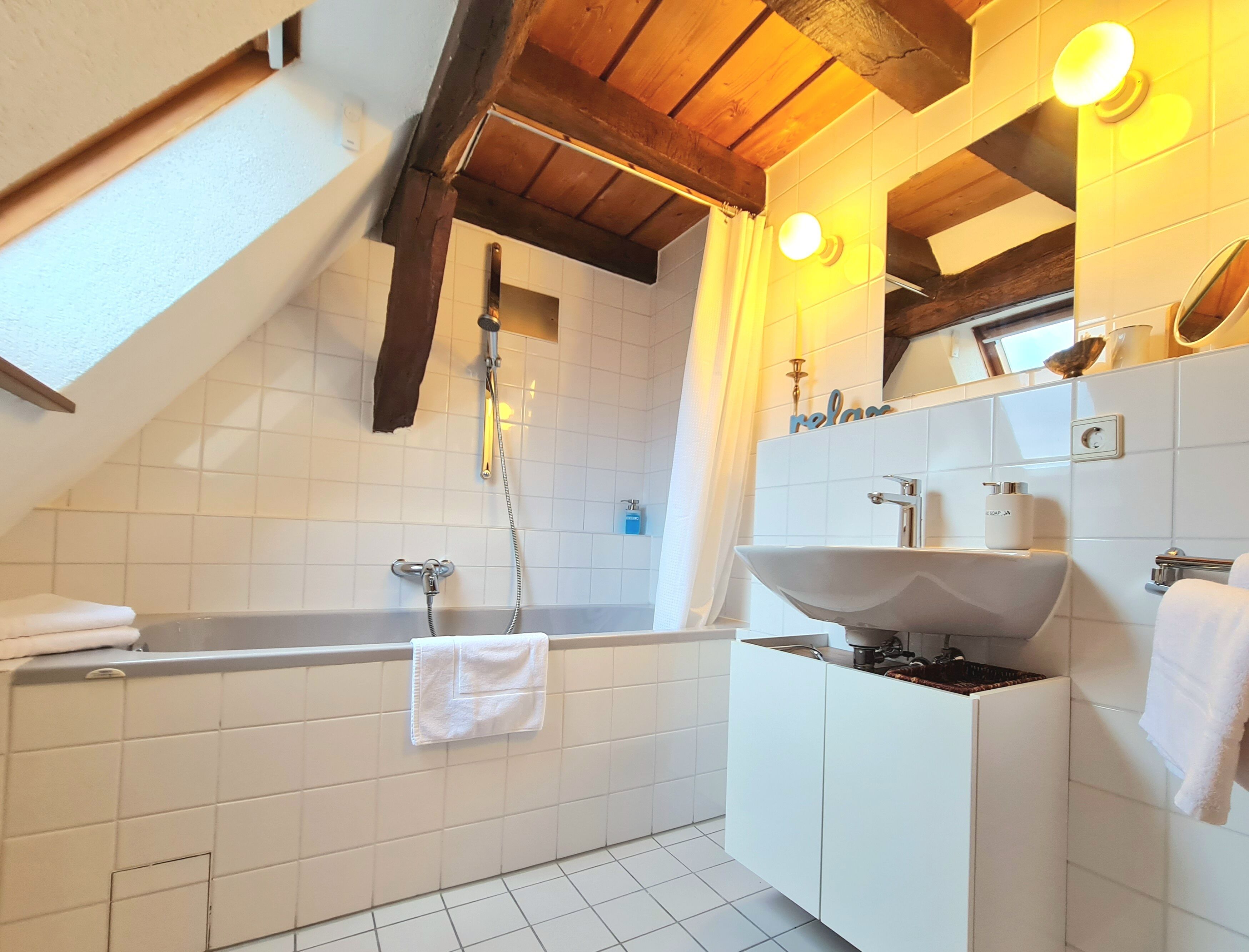 Une salle de bain moderne avec une baignoire sur pieds, un grand miroir et un lavabo blanc.