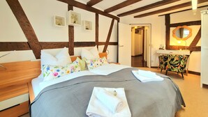 Ein Schlafzimmer mit Holzboden, einem Bett mit Blumenmuster und einem Nachttisch sowie einem Spiegel.