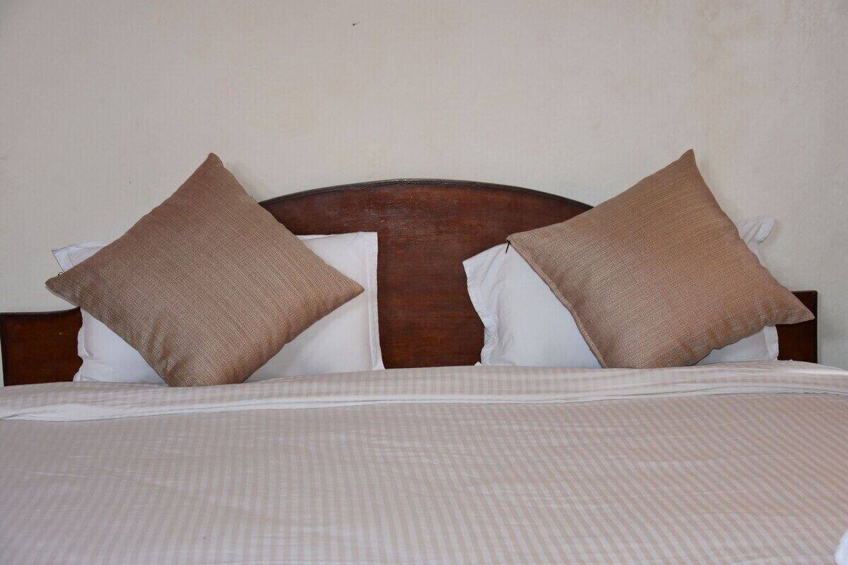 Una cama con cabecera de madera, dos almohadas y una colcha a cuadros.