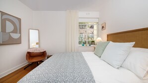 A hotel room with a bed, a chair, a window with curtains, a lamp, and a wall with a framed picture. - Pet Friendly - Charnwood Charm in St Kilda (St Kilda)