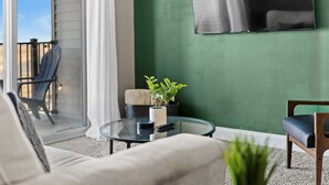 A modern living room with a glass coffee table, a sofa, a chair, and a potted plant. - Top Floor, Modern & Upgraded with Open Balcony (West Des Moines)