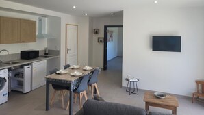 A modern kitchen with a dining area, a flat-screen TV mounted on the wall, and a small seating area with a table and chairs. - Peaceful cottage with spa and air conditioning in Couzon (Couzon)
