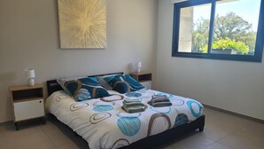 A bedroom with a bed, two bedside tables, a window, and a wall art piece. - Peaceful cottage with spa and air conditioning in Couzon (Couzon)