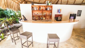 Een bar met een houten toonbank, rieten krukken en flessenkasten vol drank.
