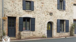 A stone building with three windows, a door, and a small garden area. - Renovated House with Shared Pool and Garden in Mareuil-sur-Lay, Sleeps 6 (Mareuil-sur-Lay-Dissais)