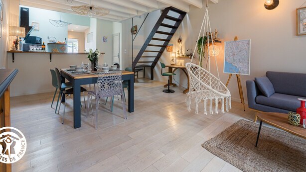A modern living room with a staircase, a dining area, and a kitchen visible through an open door. - Renovated House with Shared Pool and Garden in Mareuil-sur-Lay, Sleeps 6 (Mareuil-sur-Lay-Dissais)