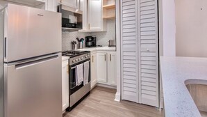Eine moderne Küche mit einem Edelstahl-Kühlschrank, einem Herd und weißen Schränken.