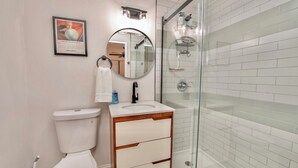 Un baño moderno con inodoro, lavamanos, tocador y cabina de ducha de vidrio.