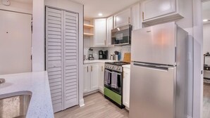 Una cocina moderna con armarios blancos, un refrigerador de acero inoxidable, una estufa a gas y un microondas.