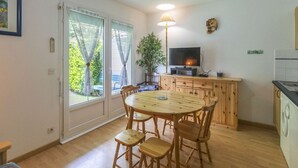 A compact living space with a dining area, a television, and a kitchen area. - Cozy 1-Bed Apartment for 4 with Garden, Parking, Near Cauterets Center and Thermal Spa (Cauterets)