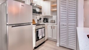 Una cocina con refrigerador, estufa, horno y alacenas.