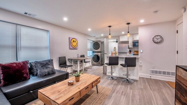 Una sala de estar moderna con un sofá, una mesa de centro y una zona de cocina con un taburete de bar.