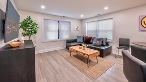 Una sala de estar moderna con un sofá, una mesa de centro y un televisor sobre un mueble.