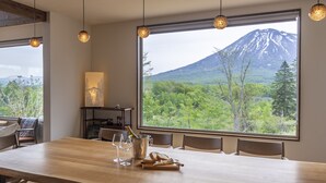 Un comedor con una mesa de madera, sillas y vistas a la montaña.