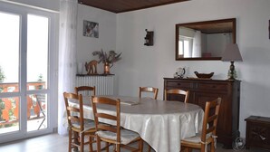 A dining room with a round table, wooden chairs, a wooden cabinet, a mirror, and a lamp.