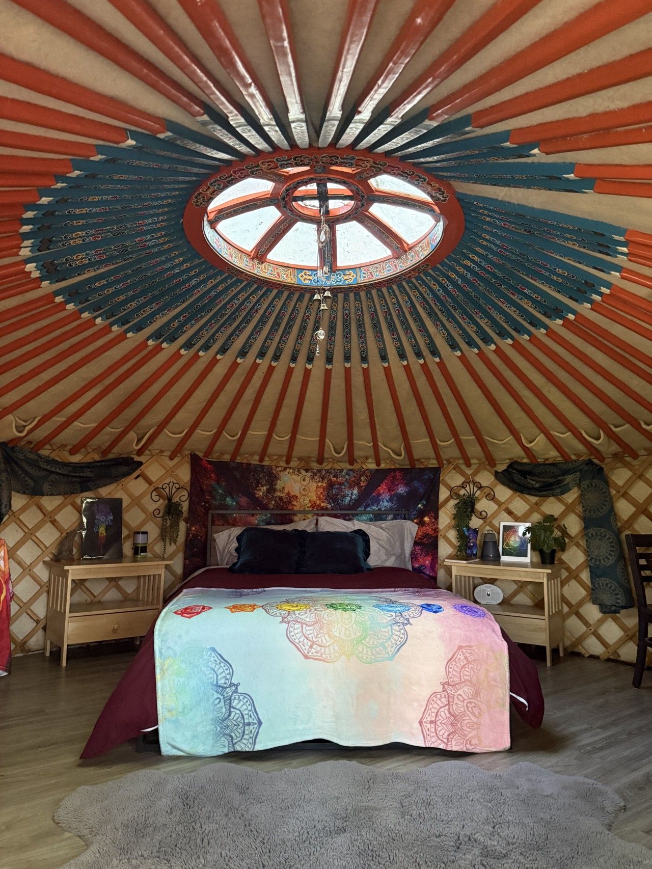 Interieur van een joert met een bed, twee nachtkastjes en een decoratief plafond.
