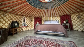 A yurt with a bed, a rug, and a window.