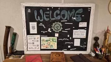 A bulletin board with a 'WELCOME' sign, a clock, and various informational cards including WiFi details and quiet hours.