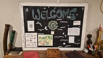 A bulletin board with a 'WELCOME' sign, a clock, and various informational cards including WiFi details and quiet hours.