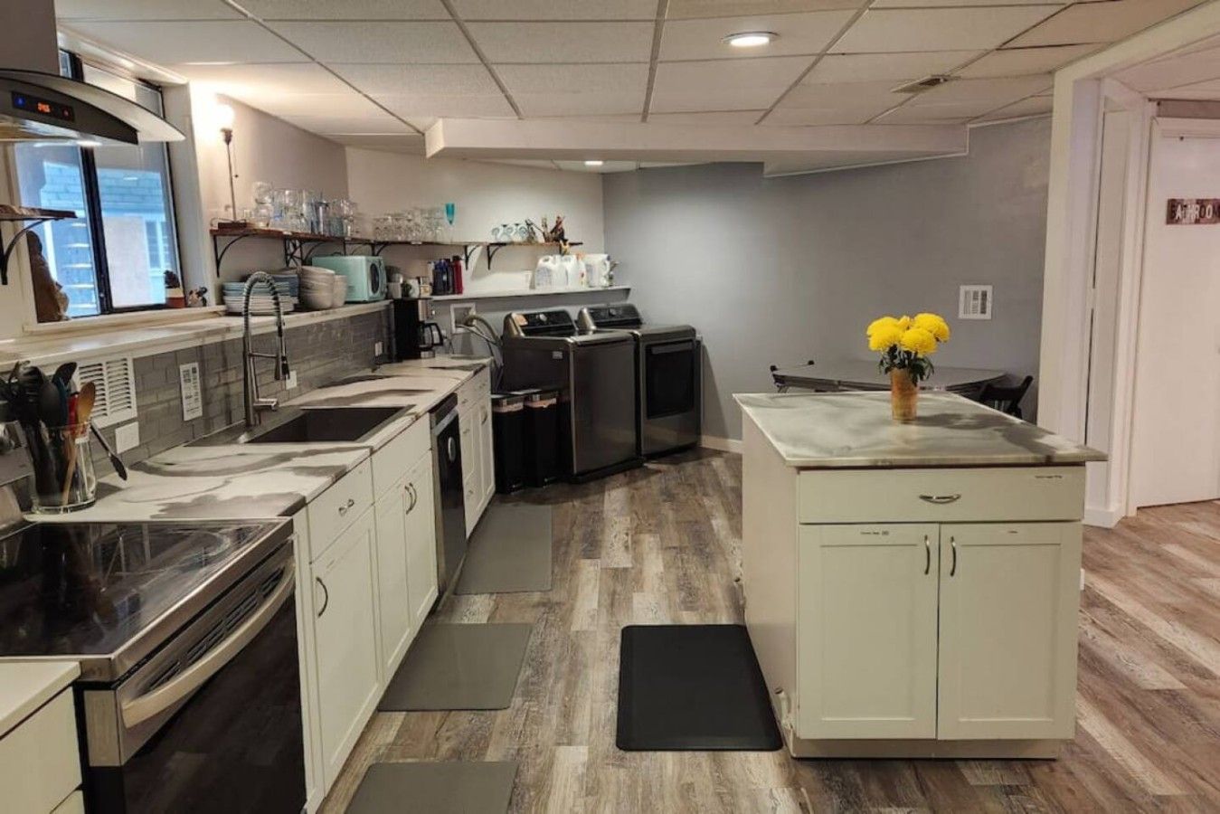A modern kitchen with stainless steel appliances, a central island, and a grey backsplash.