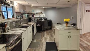 A modern kitchen with stainless steel appliances, a central island, and a grey backsplash.