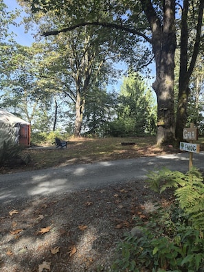 A campground with a covered area, a sign indicating a parking area, and a large tree in the background. - Gaia Yurt | Cedar Hot Tub | 1 hr to Skiing & Mt Rainier (Buckley)
