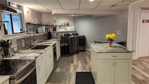 A modern kitchen with stainless steel appliances, white cabinetry, and a central island with a vase of yellow flowers.
