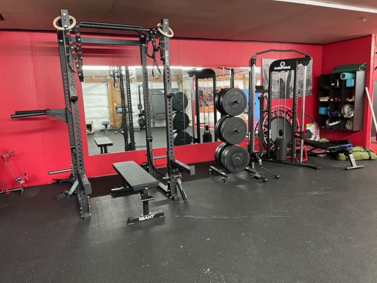 Ein Fitnessraum mit Gewichte, einer Bank und einem Spiegel.